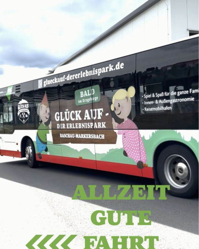 Linienbus mit Werbung für „Glück Auf – Der Erlebnispark“ und Abbildungen der Glückies.